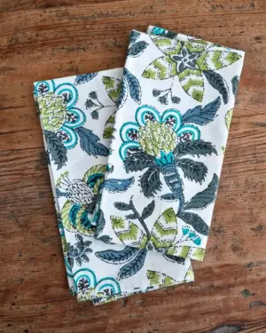 Servilletas de algodón Flor Cupido Azul con estampado floral mediterráneo en tonos azul, verde y turquesa sobre fondo blanco.