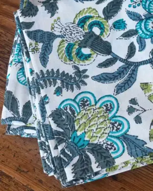 Detalle del estampado floral del mantel Flor Cupido Azul con hojas y flores en tonos azul turquesa, verde oliva y gris.