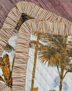 Detalle del volante de rayas y estampado de palmeras del individual acolchado Palmera Mostaza y Negro de Cassai.