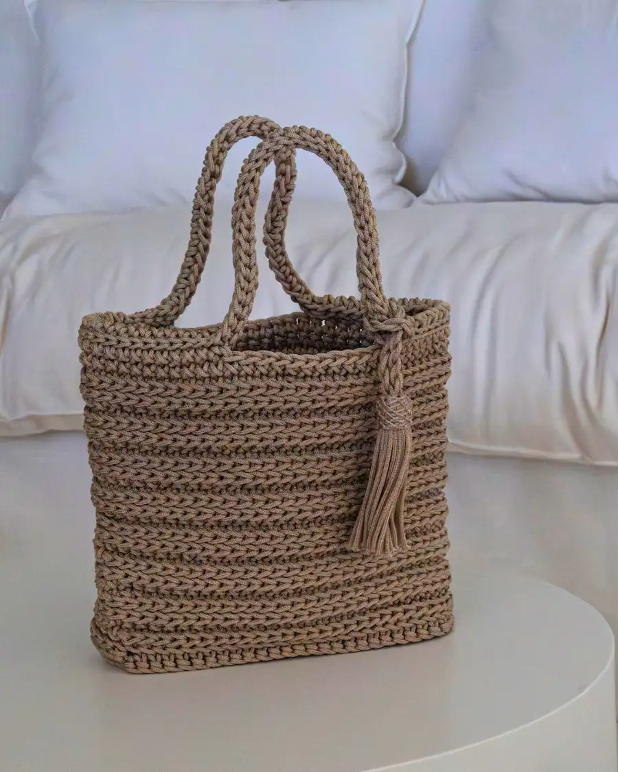 Texturas artesanales y elegancia mediterránea en un bolso tote atemporal.