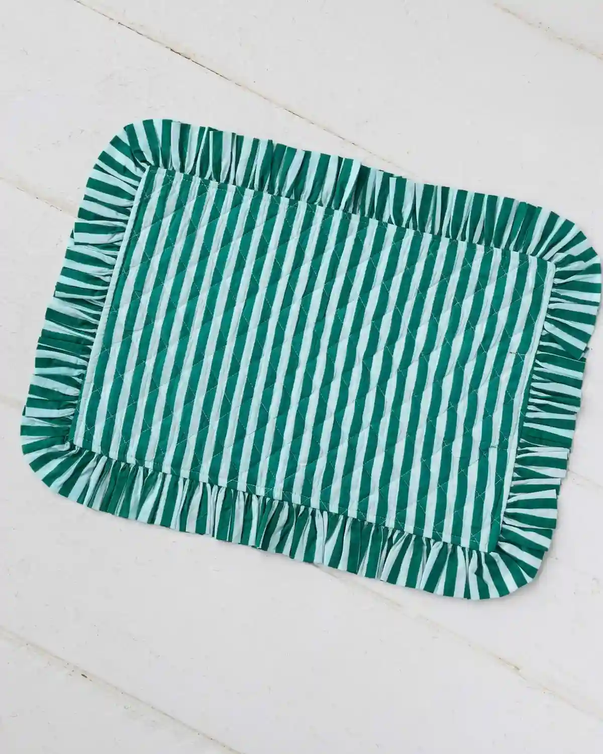 Mantel individual de algodón con rayas verdes y volante plisado, inspirado en el estilo mediterráneo para vestir la mesa con frescura y elegancia.