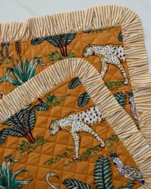 Detalle del estampado del Individual Acolchado Jungla Amarillo con ilustración de leopardo, vegetación exótica y volante de rayas.