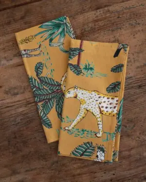 Servilleta de tela de algodón con estampado de leopardo, hojas tropicales y motivos de jungla en tonos mostaza, verde y blanco, diseño exclusivo de inspiración mediterránea.