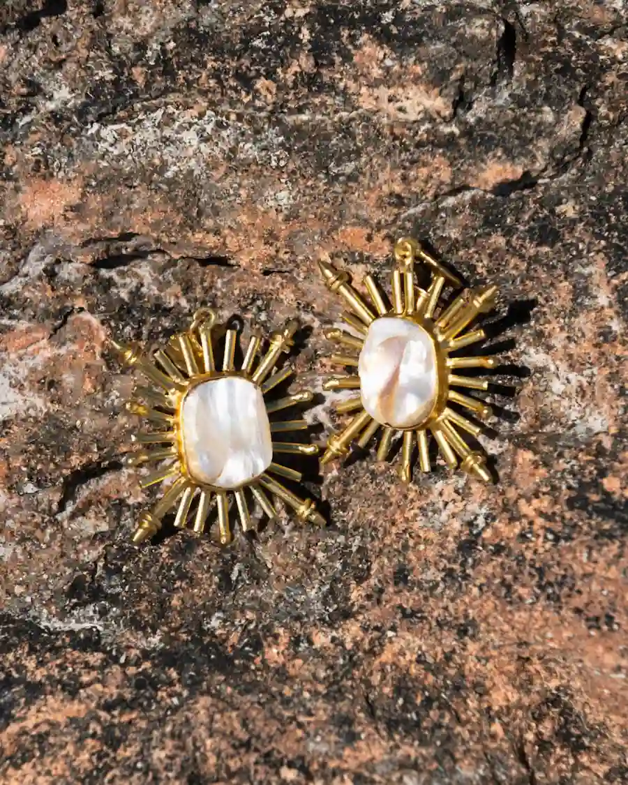 Pendientes dorados con rayos de sol y perla de nácar natural, inspirados en la luz del Mediterráneo.

