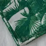 Mantel de algodón con estampado de palmeras verdes sobre fondo claro de la colección Cassai Home & Fashion