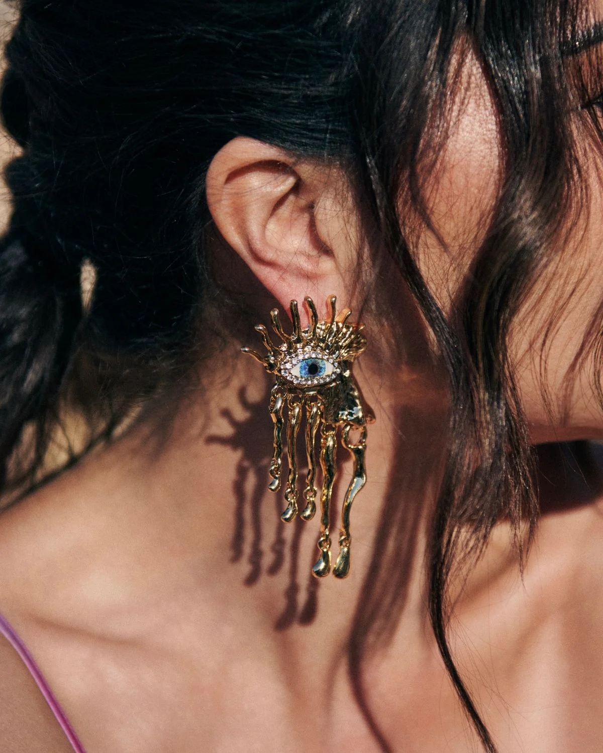 Los Pendientes Dorados Ojos de Zeus destacan por su diseño escultórico colgante con simbología protectora, aportando carácter y elegancia a la pieza.