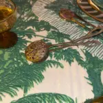 Servidor plateado con diseño de león redondo sobre mantel tropical verde en mesa decorada