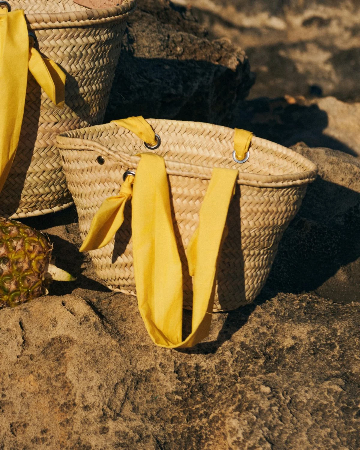 Cesta de palmito mediana con asas amarillas, un accesorio fresco y natural para los looks de verano.