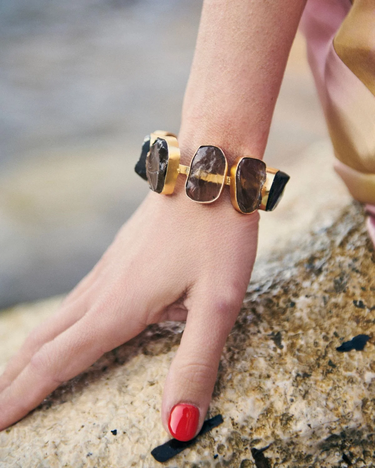 El Brazalete Piedras Oscuras destaca por su diseño orgánico y elegante, combinando el dorado con tonalidades profundas que aportan sofisticación y carácter.