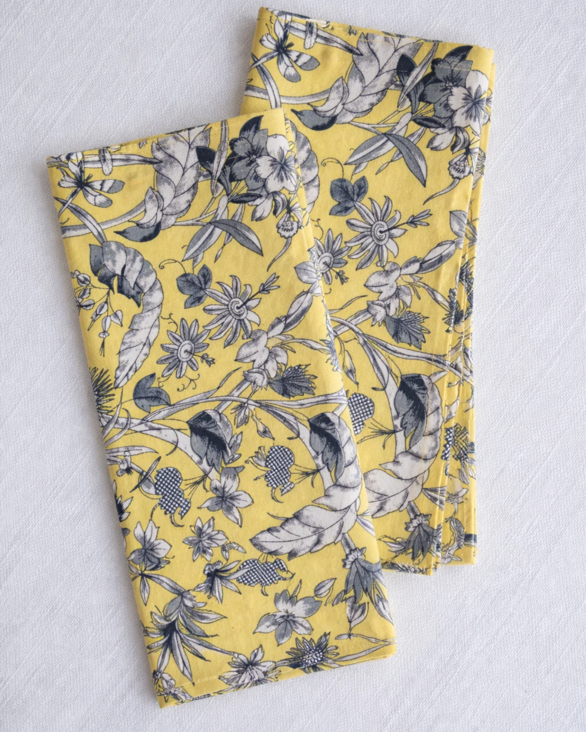 Servilleta de algodón con estampado de flores y mariposa sobre fondo amarillo. Diseño exclusivo de Catalina Socias para Cassai Mallorca, Collection 2025.