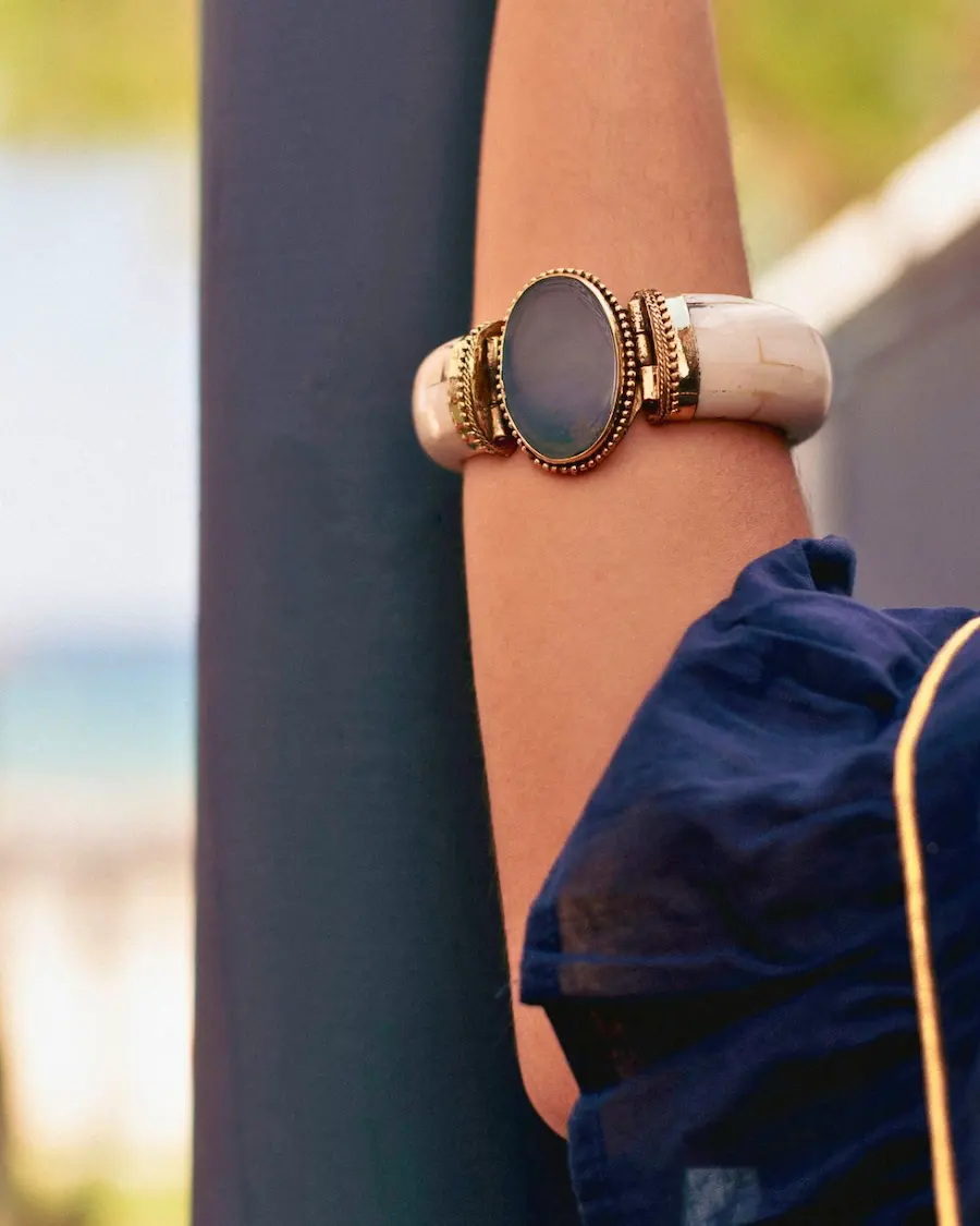 Brazalete Azul Negro Mate en muñeca · Piedra gris azulada mate · Latón dorado envejecido · Outfit azul marino · Selección Especial Cassai