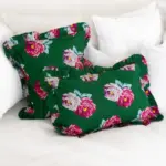 cojín decorativo floral verde con volantes sobre cama blanca estilo mediterráneo