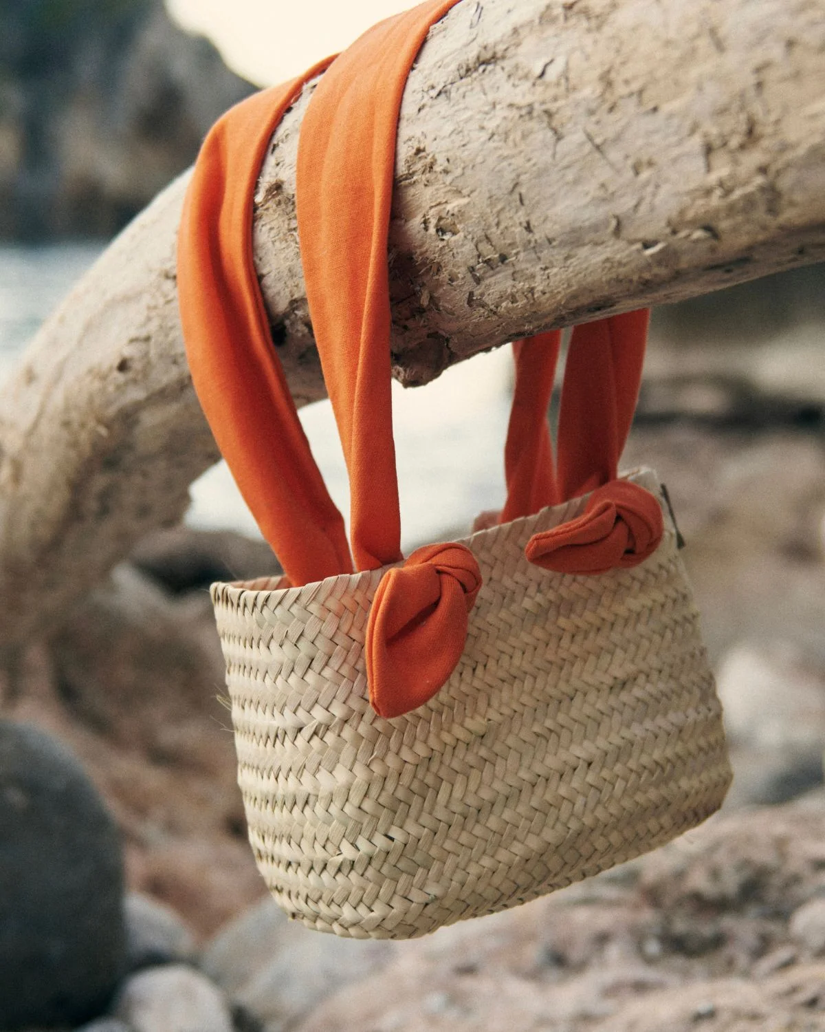Capazo de playa pequeño de palmito con asas de tela naranja, ideal para looks veraniegos.