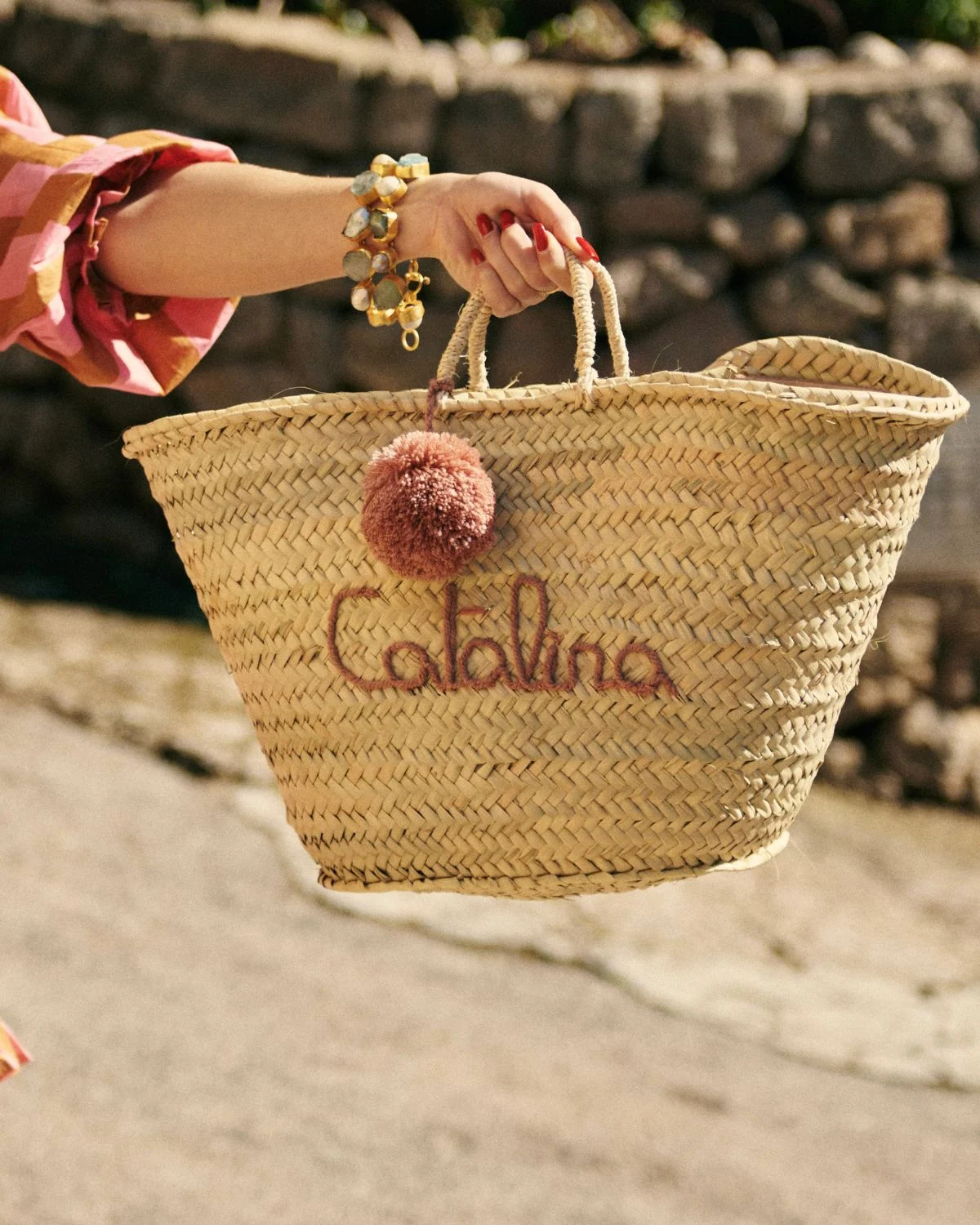 Capazo de playa de palmito con bordado rosado Catalina y borla decorativa, inspirado en la estética mediterránea.