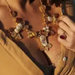 Collar Flor Primavera Maxi bañado en dorado con piedras de cuarzo rosado y perlas barrocas, usado sobre blusa color camel en luz natural