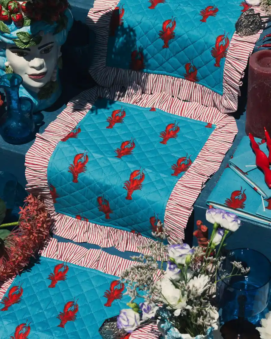 Mantel individual acolchado con estampado de langostas rojas sobre fondo azul Capri, inspirado en el Mediterráneo.