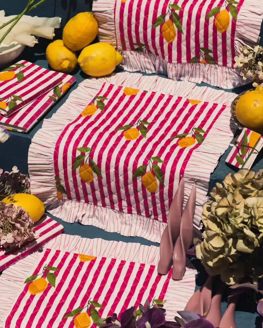 Mantel individual acolchado con rayas fucsia, estampado de limones y volante decorativo inspirado en el estilo mediterráneo.