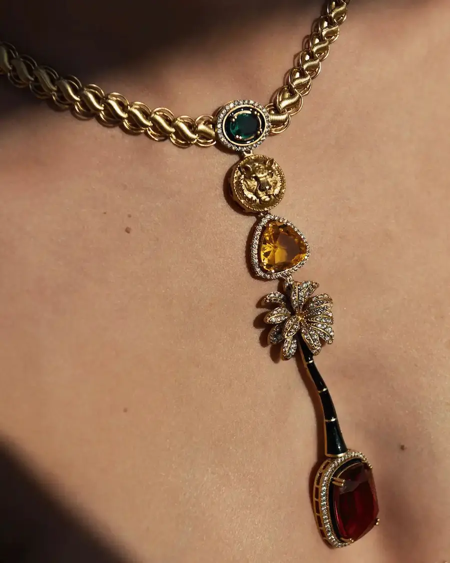 Collar Oasis Imperial Mediterráneo con cadena dorada y colgante de inspiración vintage que combina el león, la palmera y cristales en tonos verde, ámbar y granate.