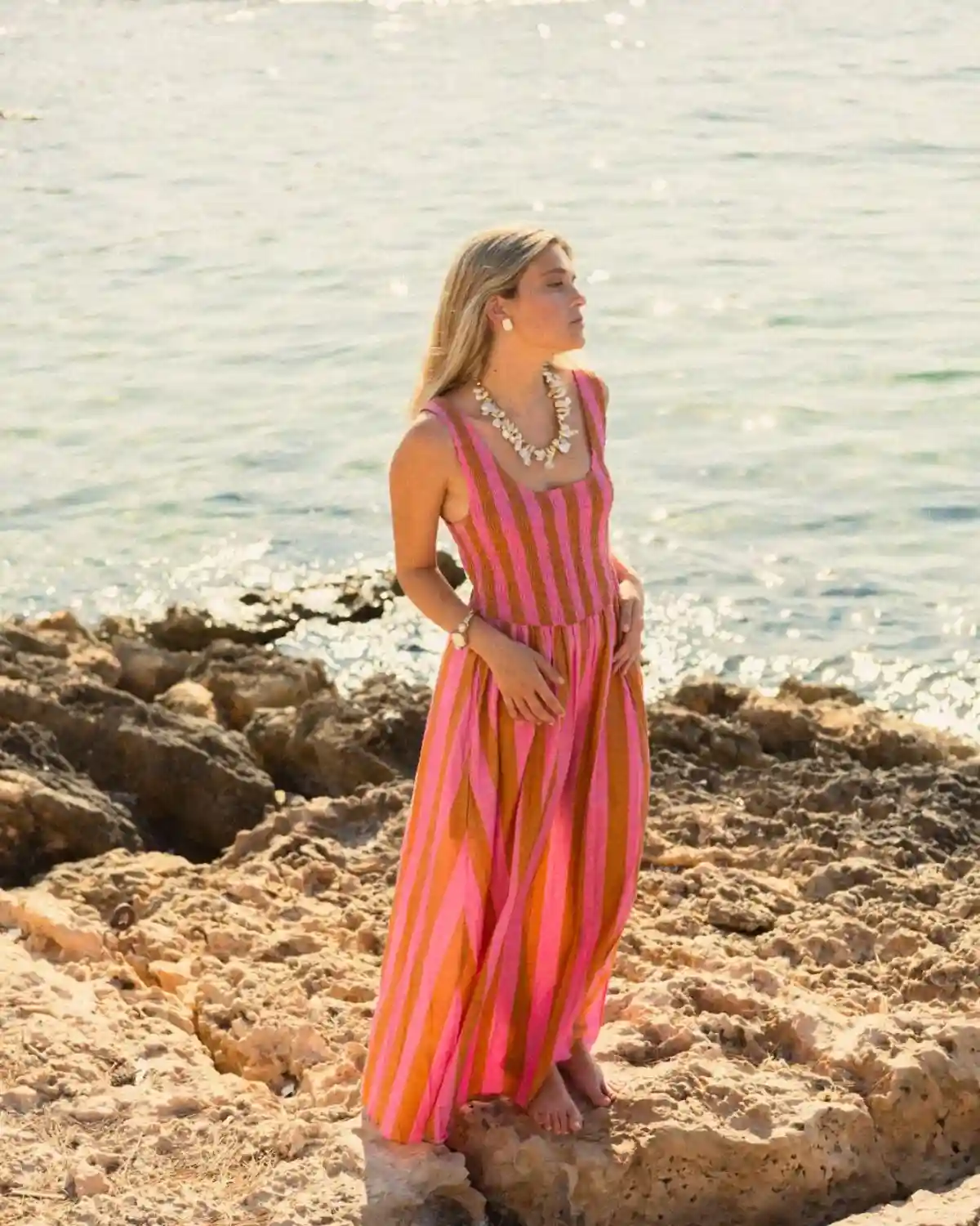 Vestido largo de rayas verticales en tonos rosa mediterráneo confeccionado en algodón natural, perfecto para vacaciones, playa y verano.