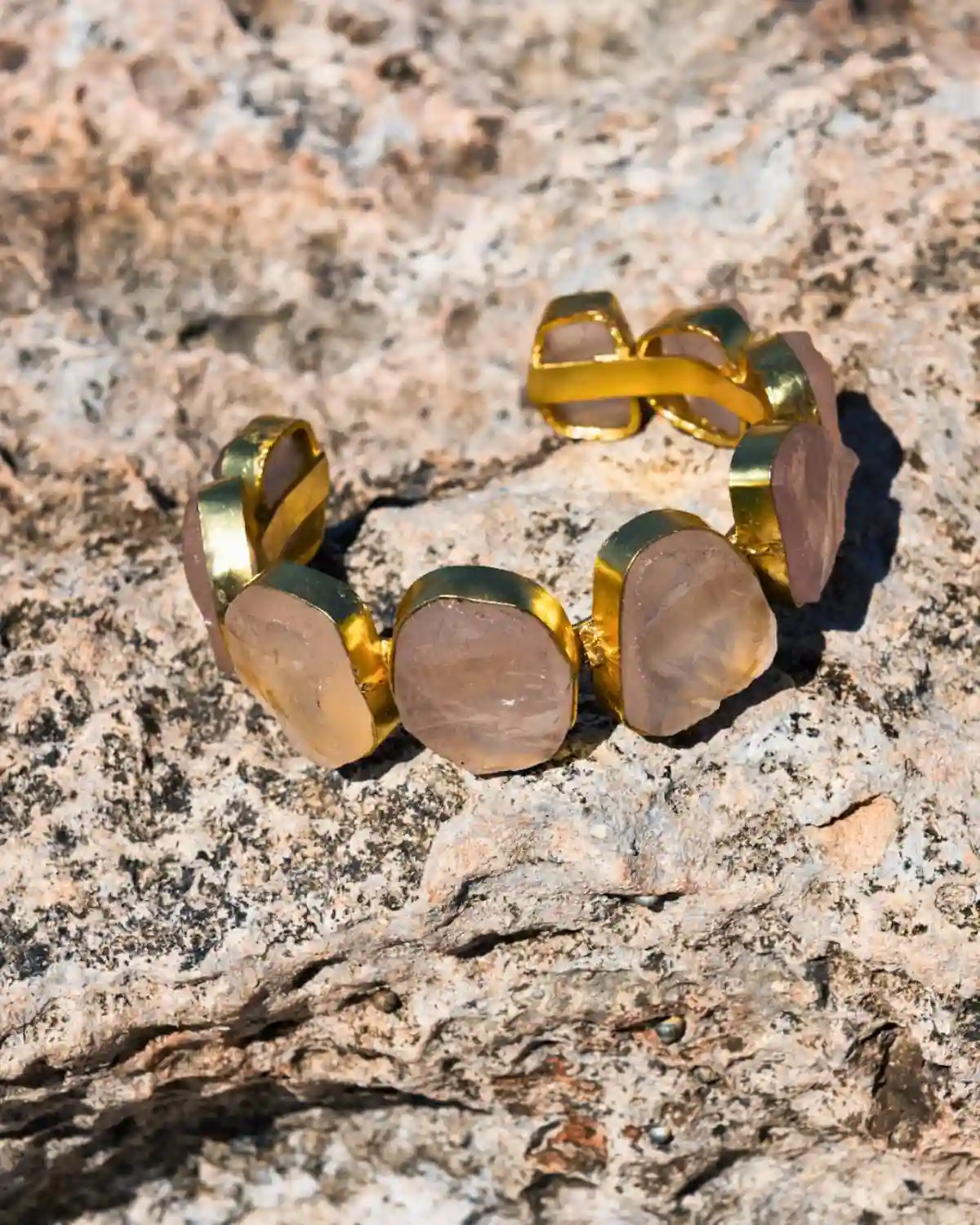 El Brazalete Aura combina piedras semipreciosas en tonos rosados y beige con un acabado en bronce dorado, inspirado en la luz cálida del Mediterráneo.