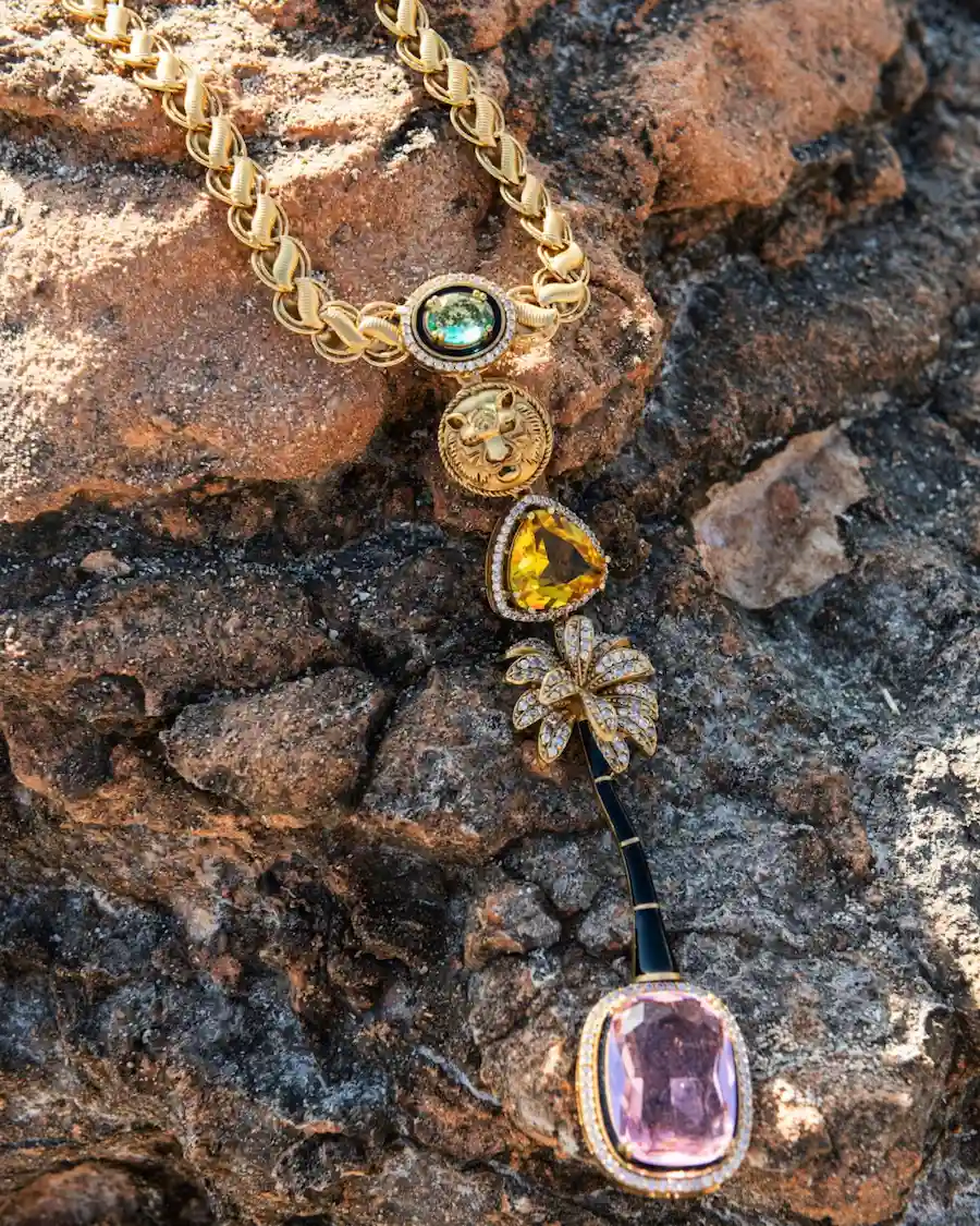 El Collar Oasis Rosa Cassai Home combina una cadena de eslabones dorados, cristales de colores y un colgante de inspiración vintage con cabeza de león y palmera, evocando la esencia del Mediterráneo.