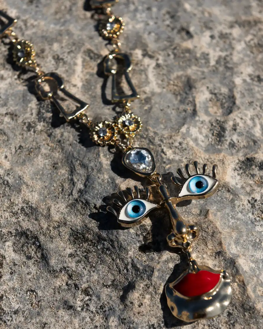 Collar artesanal inspirado en el ojo turco y el surrealismo, elaborado en latón bañado en oro de 18K con detalles esmaltados y cristales.