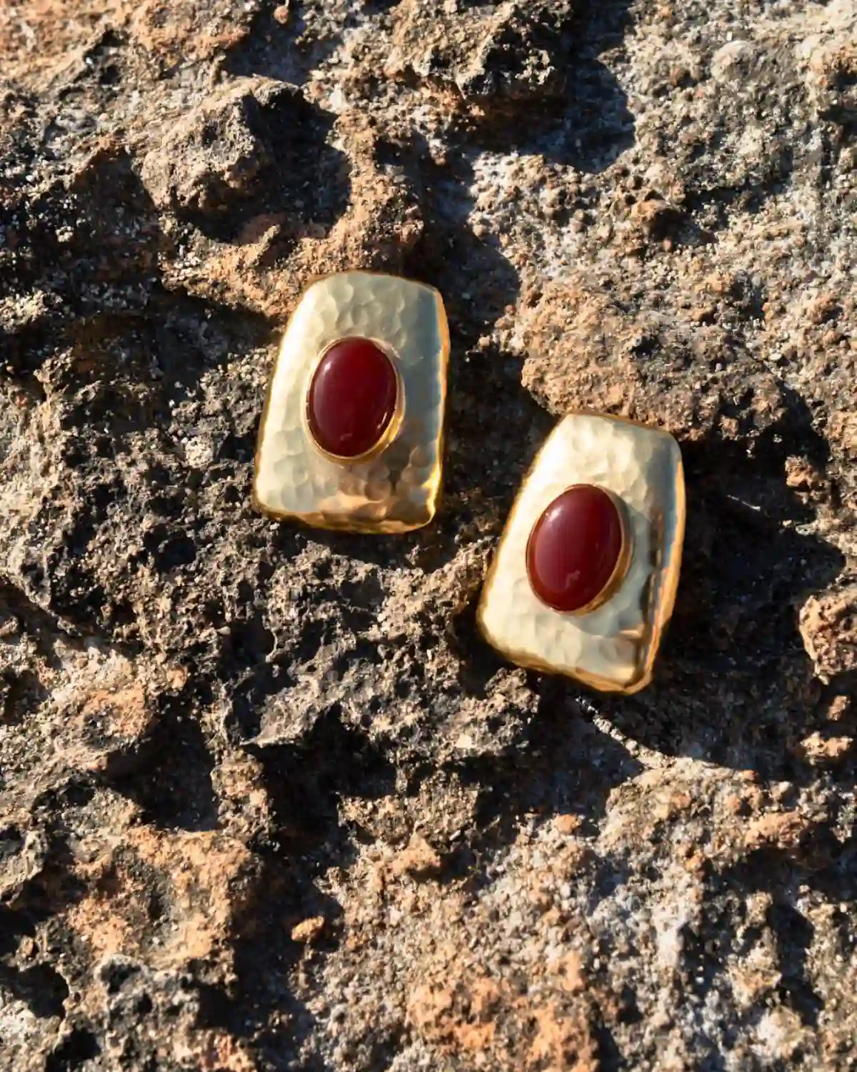 Detalle de los Pendientes Órbita Rubí con textura martillada y piedra roja de inspiración contemporánea.