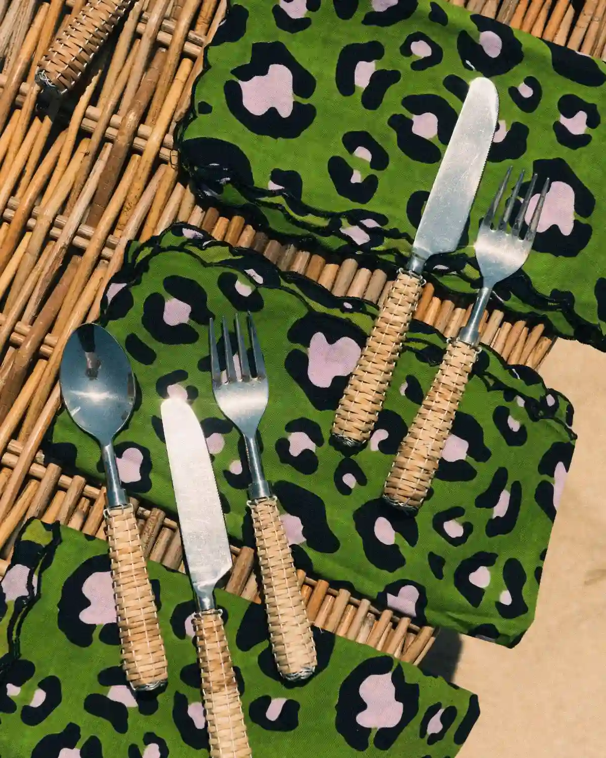 Servilletas Animal Print Verde con borde festoneado, acompañadas de cubiertos de ratán.