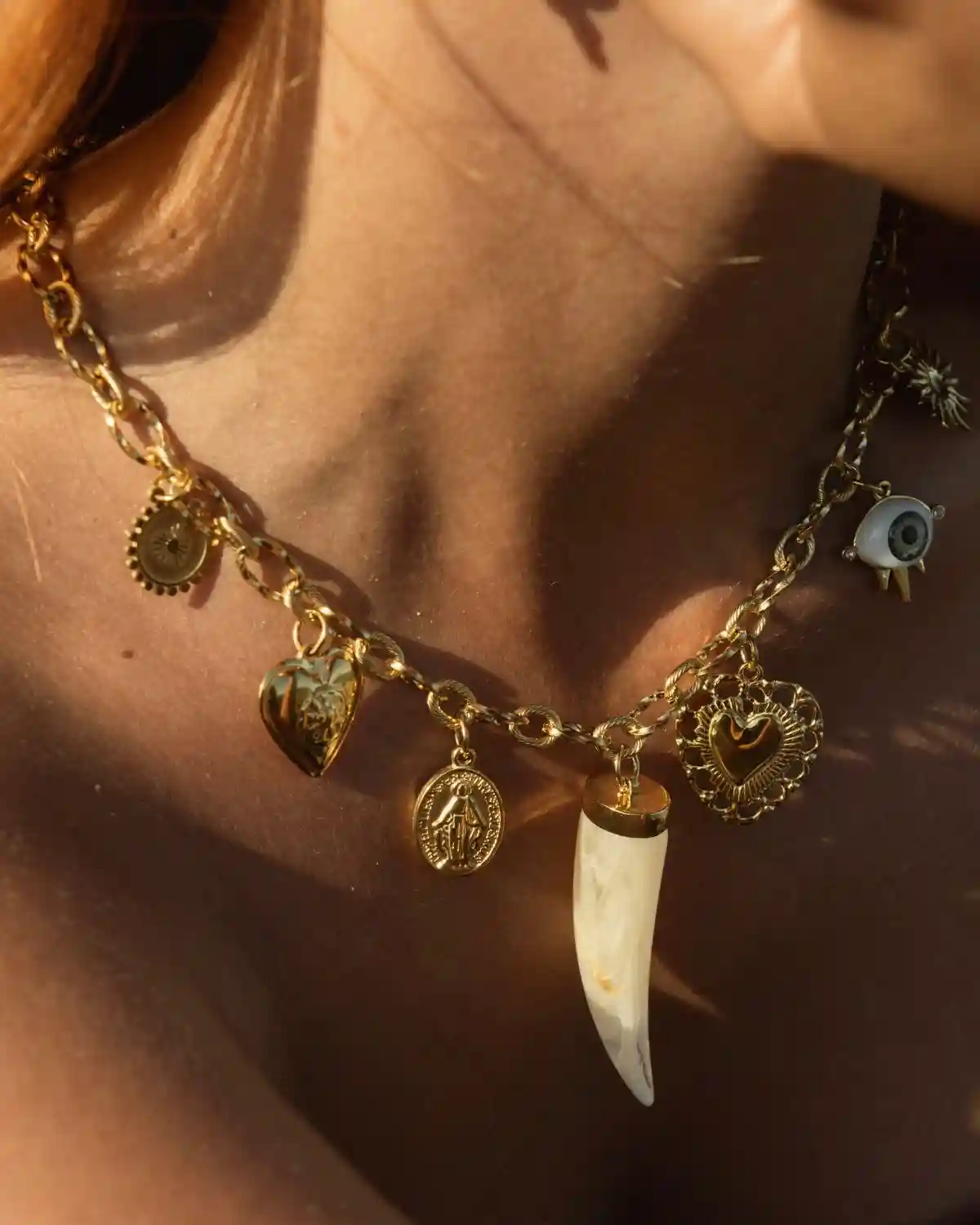 Collar Tresor Mediterráneo con cadena dorada y siete charms de inspiración simbólica.