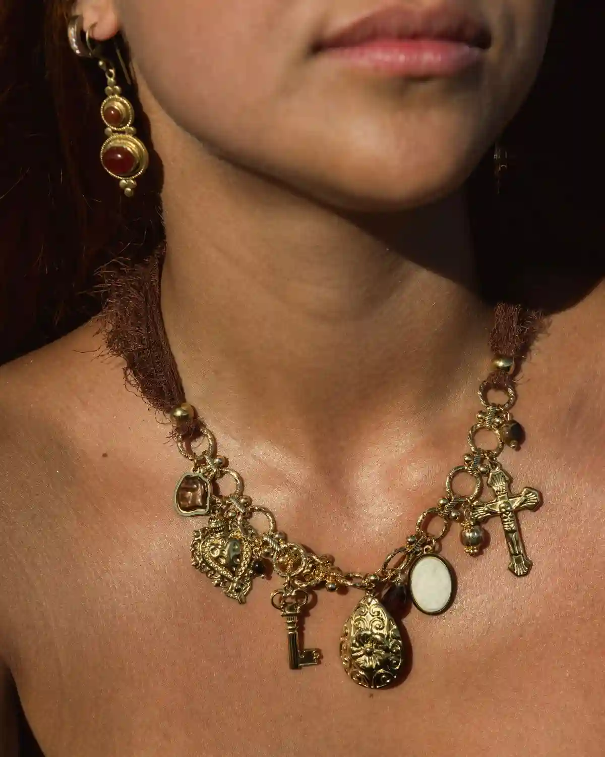 Collar Relíquia Mediterránea de tela con charms y amuletos dorados.