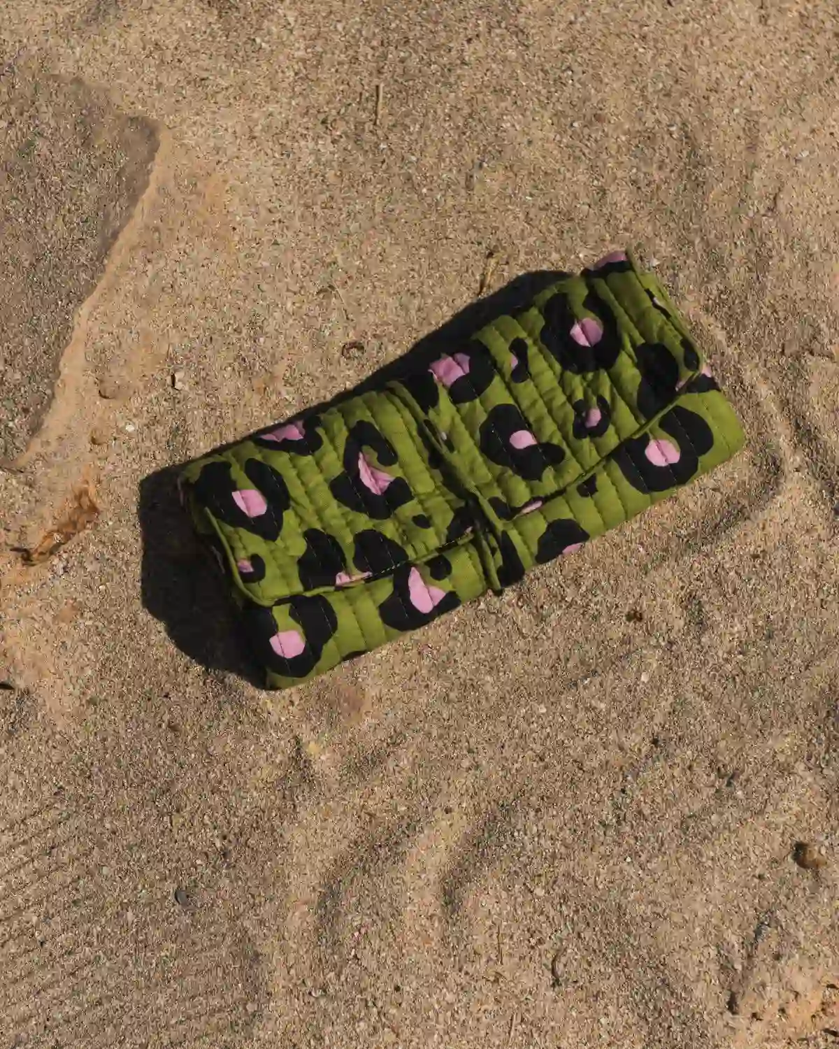 Bolsa de maquillaje acolchada Animal Print Verde enrollada y cerrada con cordón a juego.