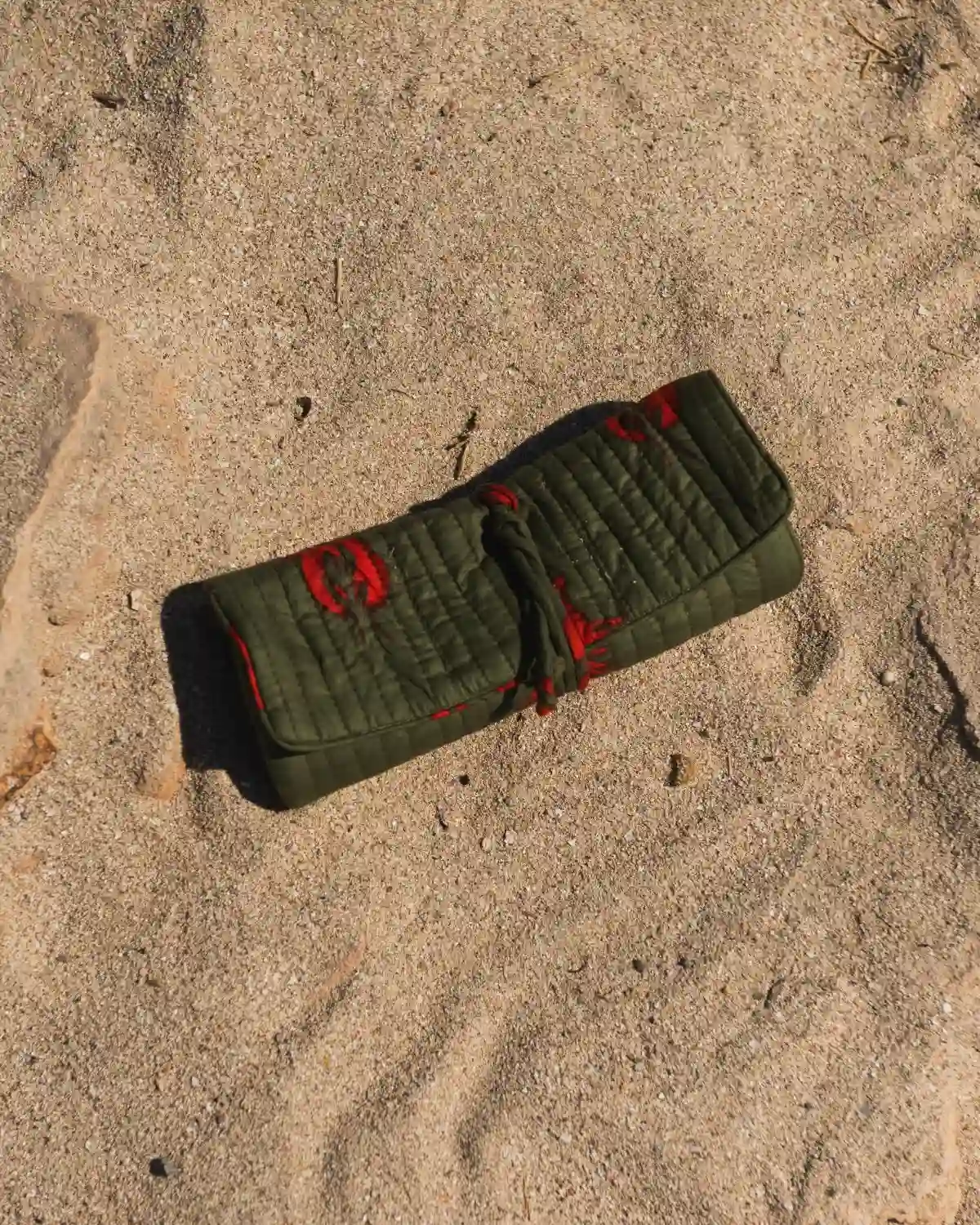 Bolsa de maquillaje acolchada con langostas rojas sobre verde oliva, enrollada y cerrada con cordón a juego.