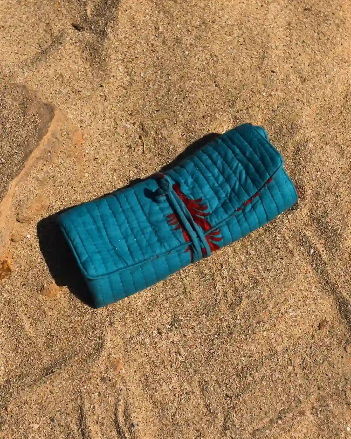 Bolsa de maquillaje acolchada Langosta Capri enrollada y cerrada con cordón a juego.